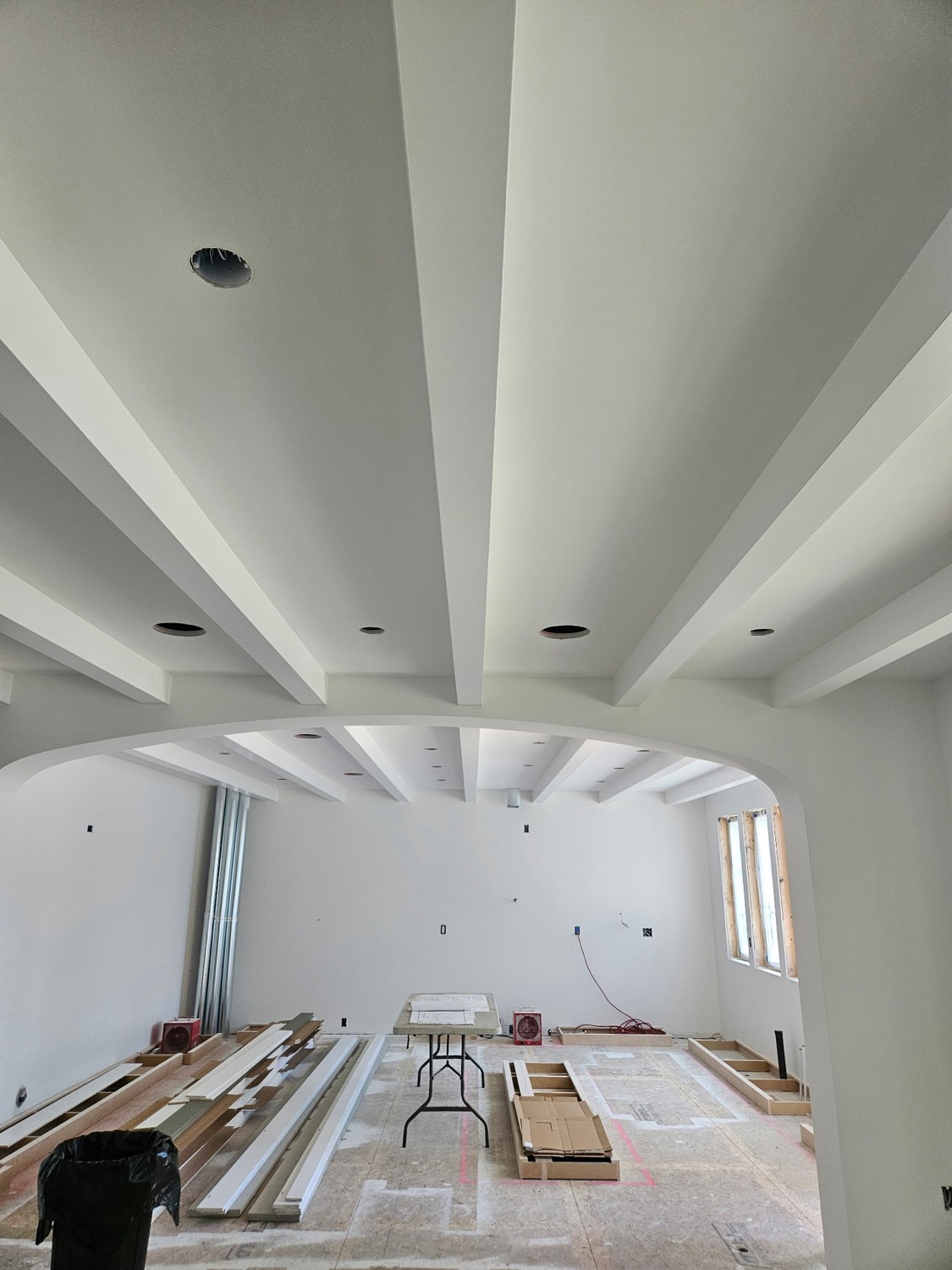 Custom beamed and coffered ceiling across a great room with a curved archway